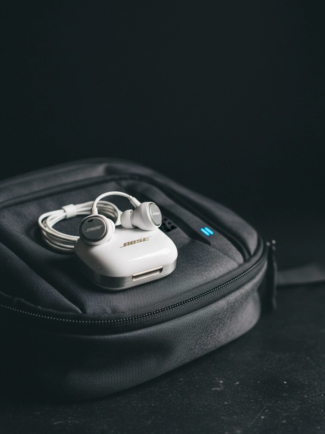 Par de earbuds inalámbricos TOZO blancos junto a su estuche de carga abierto sobre superficie de aluminio oscuro.
